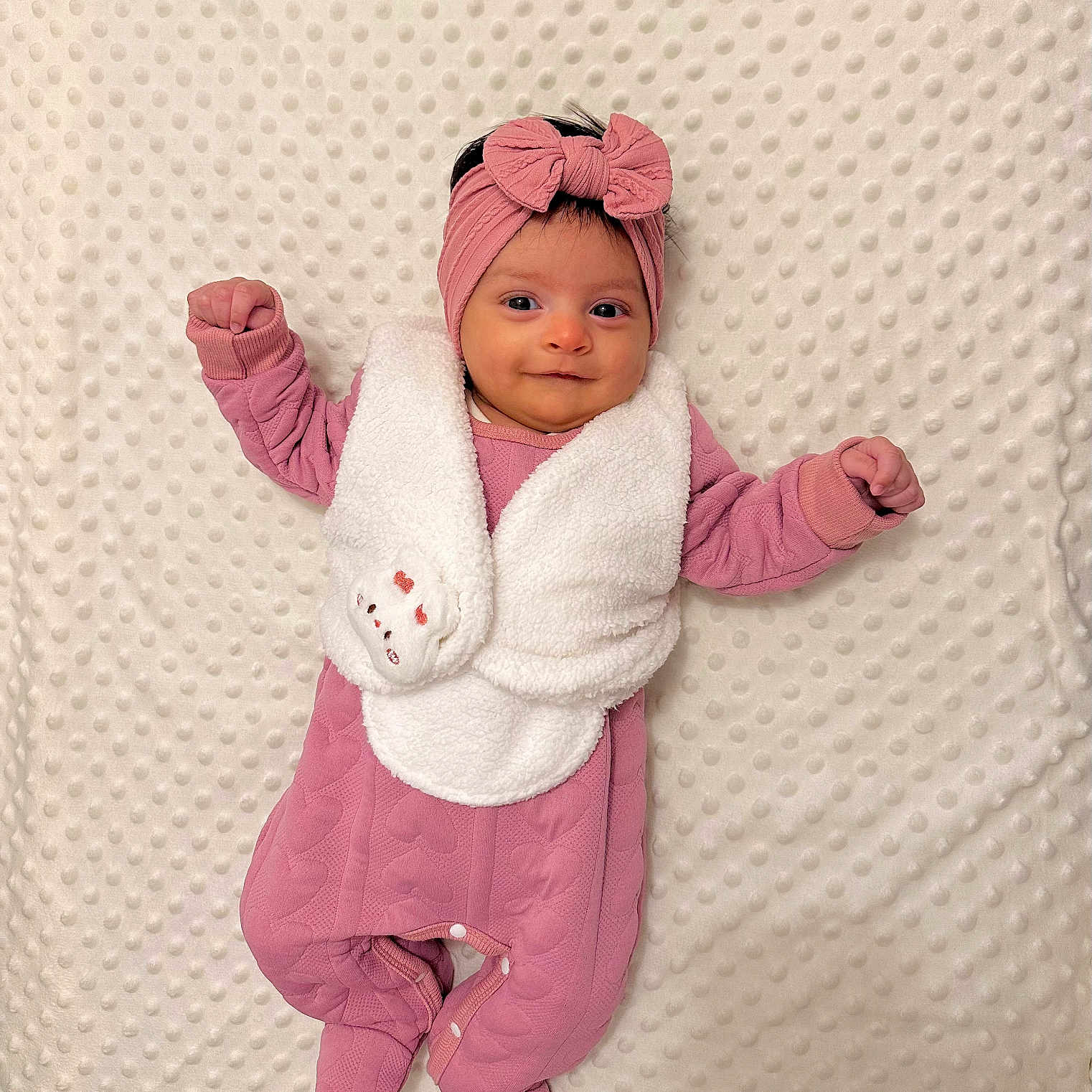 éline a rejoint le concours — aidez-le/la à gagner de superbes lots ! baby, blanket, bow, child, cozy, cute, footed_pajamas, happy, headband, indoor, infant, lying_down, newborn, pink_clothing, portrait, raised_arms, sleepwear, smiling, soft, textured_blanket