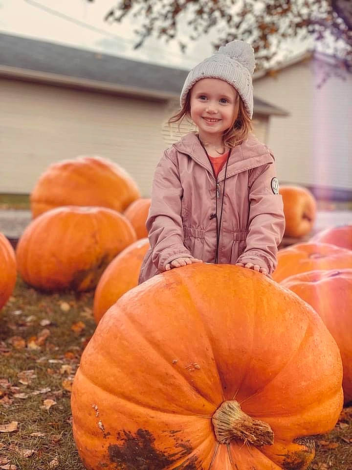 Evie is registered to the contest to win money with this photo: calabaza, child, cucurbita, eye, face, gourd, happy, head, headwear, jacket, joy, natural_foods, orange, people_in_nature, person, photograph, plant, pumpkin, smile, squash