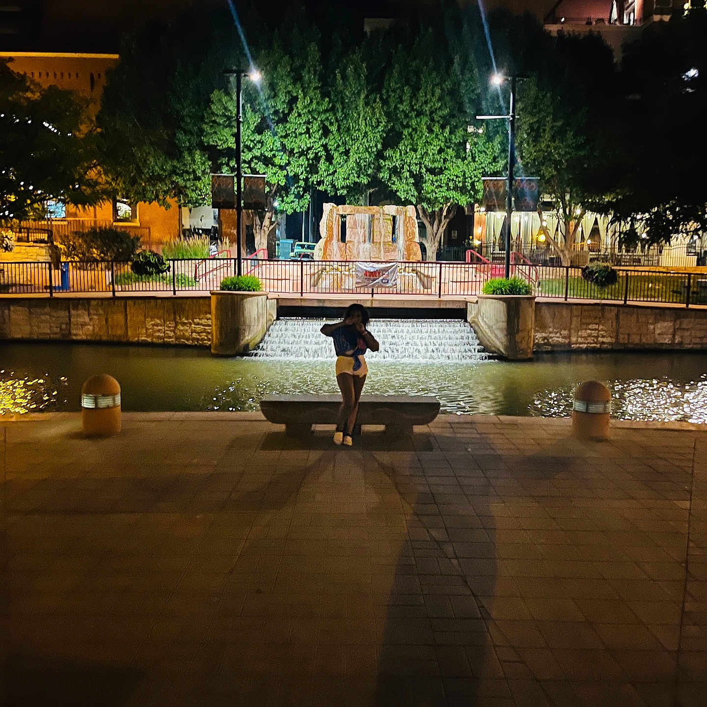 Zoey is registered to the contest to win money with this photo: architecture, bench, city, clothing, flagstone, footwear, fountain, furniture, lighting, nature, night, outdoors, path, person, plant, shoe, tree, urban, walkway, water