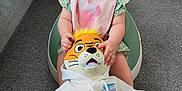 Elodie joined the competition — help win amazing prizes! baby, child, smiling, sitting, toy, plush_toy, tiger, hoodie, blue_eyes, hair_tie, baby_seat, carpet, couch, indoor, cute, happy, person, infant, clothing, living_room