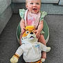 baby, child, smiling, sitting, toy, plush_toy, tiger, hoodie, blue_eyes, hair_tie, baby_seat, carpet, couch, indoor, cute, happy, person, infant, clothing, living_room