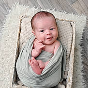 Kobe joined the competition — help win amazing prizes! baby, infant, smile, blanket, basket, wrapped, cute, face, head, hands, feet, floor, rug, woven_basket, cozy, portrait, newborn, child, indoor, soft