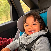 Giovanni is registered to the contest to win money with this photo: toddler, child, car_seat, smile, happy, seatbelt, blanket, hoodie, car_interior, window, safety, baby, young_child, seat, travel, road_trip, casual_clothing, person, indoor, cute