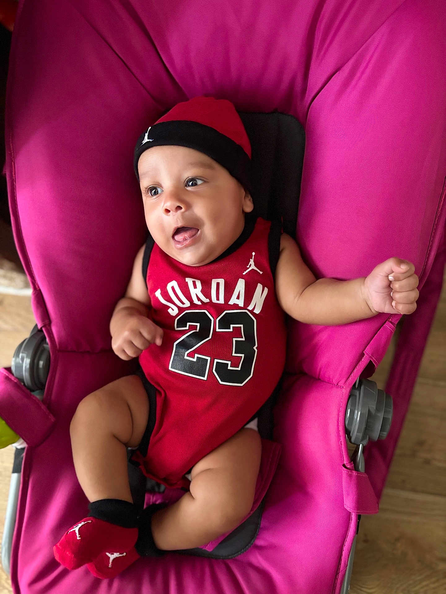 Isaiah a rejoint le concours — aidez-le/la à gagner de superbes lots ! baby, infant, child, jordan, red_clothing, hat, socks, stroller, pink, smiling, happy, cute, indoors, portrait, person, young, seated, playful, face, expression