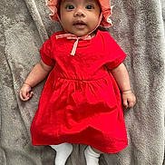 Zoé a rejoint le concours — aidez-le/la à gagner de superbes lots ! baby, infant, red_dress, pink_hat, white_socks, blanket, lying_down, cute, face, wide_eyes, soft_texture, child, adorable, portrait, young_child, indoors, clothing, headwear, smiling, skin