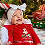 Evelyn joined the competition — help win amazing prizes! baby, infant, smiling, red_clothing, headband, christmas, holiday, presents, gift_wrap, basket, decorations, tree, lights, festive, happy, cute, indoors, celebration, toddler, portrait