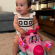 Aslihan joined the competition — help win amazing prizes! toddler, child, toy_airplane, pink_toy, minnie_mouse, indoor, carpet, living_room, cute, playful, smiling, baby, person, short_hair, clothing, foot, furniture, television, decor, light