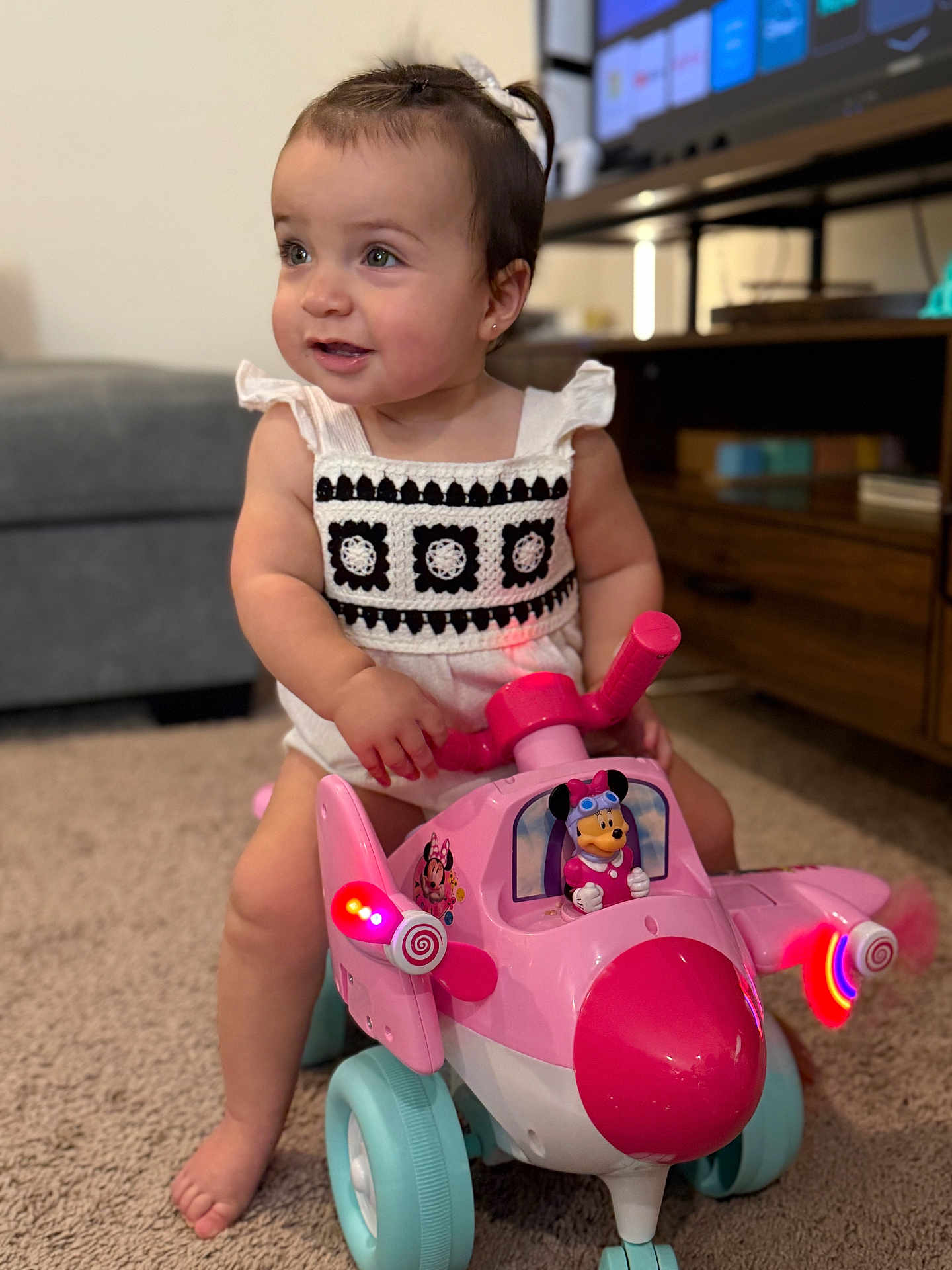 Aslihan joined the competition — help win amazing prizes! toddler, child, toy_airplane, pink_toy, minnie_mouse, indoor, carpet, living_room, cute, playful, smiling, baby, person, short_hair, clothing, foot, furniture, television, decor, light