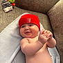 baby, infant, smiling, red_hat, blanket, couch, clapping_hands, diaper, skin, cute, chubby, indoors, soft_lighting, happy, child, toddler, cozy, furniture, headwear, portrait