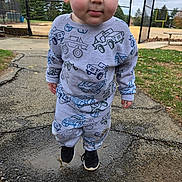 Ryder is registered to the contest to win money with this photo: autumn_leaves, blue_eyes, car_prints, chainlink_fence, child, curious_expression, face, grass, gray_sweatshirt, outdoor, pavement, playground, portrait, puddle, rosy_cheeks, sneakers, sports_field, standing, toddler, trees