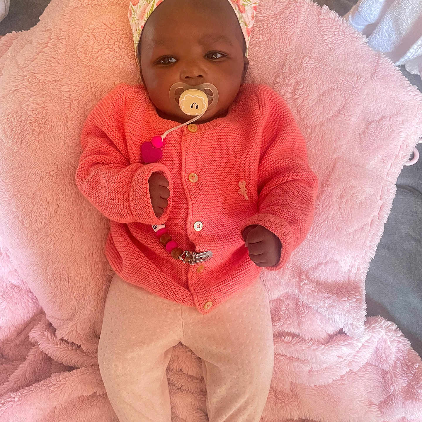 Léna Astou a rejoint le concours — aidez-le/la à gagner de superbes lots ! adorable, baby, baby_accessory, baby_clothing, child, comfortable, cute, floral_pattern, headband, indoors, infant, knit_sweater, lying_down, newborn, pacifier, peaceful, pink_blanket, portrait, sleepwear, soft_texture