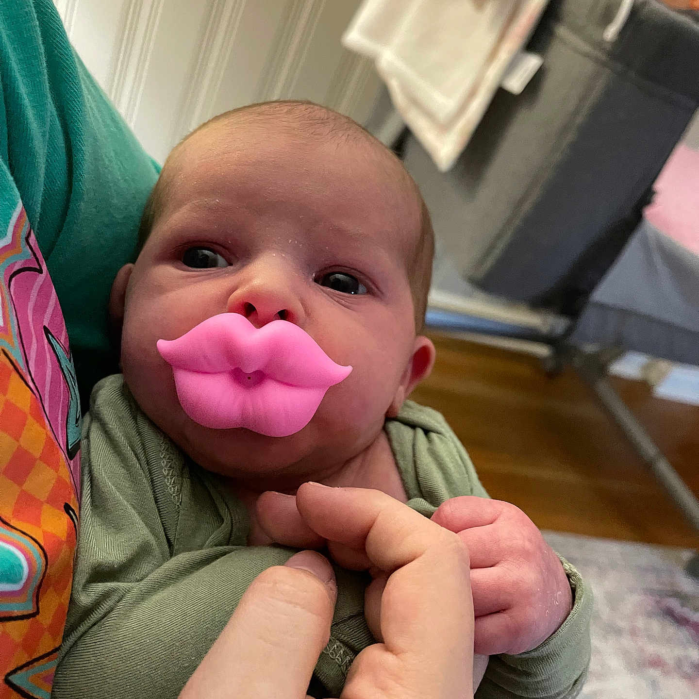 Elsie is registered to the contest to win money with this photo: baby, background, carpet, clothing, cute, expression, face, furniture, hand, holding, indoors, infant, lips, newborn, pacifier, person, pink, skin, sleeve, toy