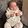 baby, infant, milestone_card, clothing, pillow, fluffy, cute, face, hand, foot, sitting, patterned_clothes, pink, white, indoor, portrait, child, young_baby, couch, soft_texture