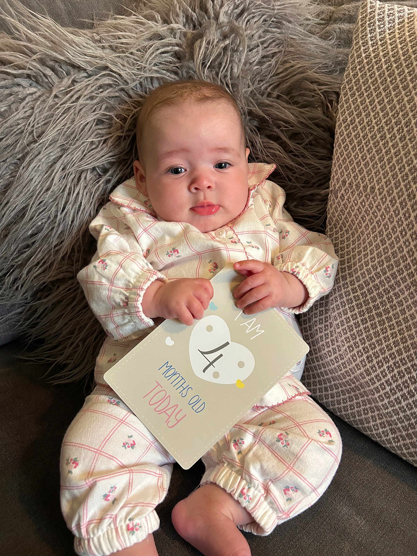 Nellè is registered to the contest to win money with this photo: baby, infant, milestone_card, clothing, pillow, fluffy, cute, face, hand, foot, sitting, patterned_clothes, pink, white, indoor, portrait, child, young_baby, couch, soft_texture