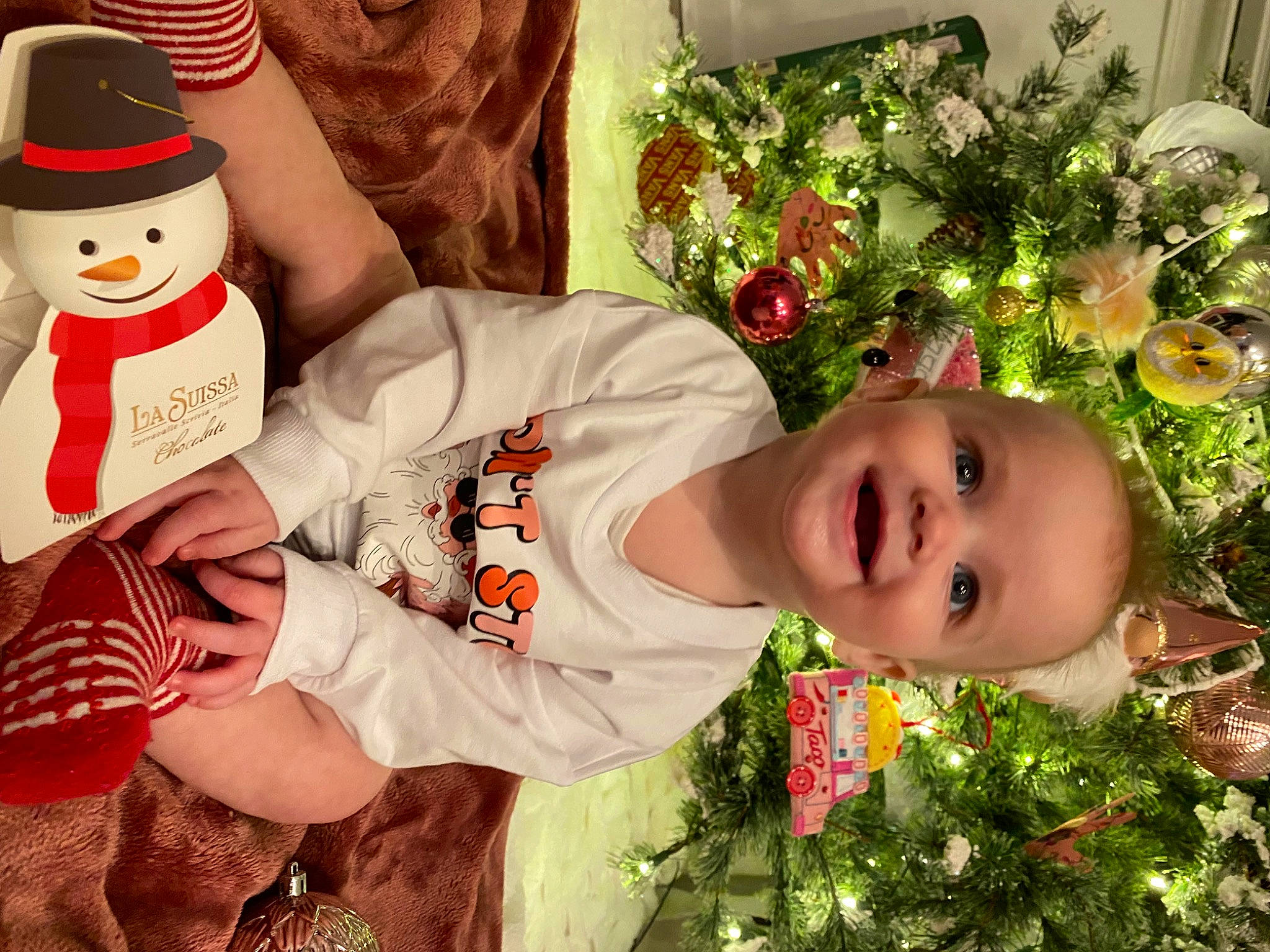 Elliott is registered to the contest to win money with this photo: baby_toddler_clothing, child, christmas, christmas_eve, christmas_ornament, costume_hat, event, facial_expression, flower, flower_arranging, grass, happy, hat, holiday, joy, people_in_nature, person, plant, red, smile