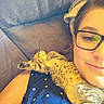person, glasses, kitten, cat, resting, couch, polka_dot, shirt, relaxation, indoor, close_up, feline, pet, sleeping, cozy, comfort, young_cat, fur, spots, stretching