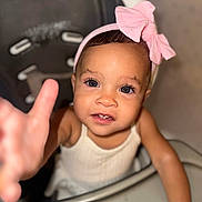 Serenity is registered to the contest to win money with this photo: toddler, child, baby, high_chair, pink_bow, headband, reaching_hand, curious, portrait, indoor, face, eyes, skin, clothing, expression, person, furniture, seat, closeup, cute