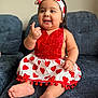 baby, child, smiling, sitting, dress, headband, heart_pattern, red, white, couch, indoor, cute, cheerful, happy, portrait, infant, person, furniture, skin, foot