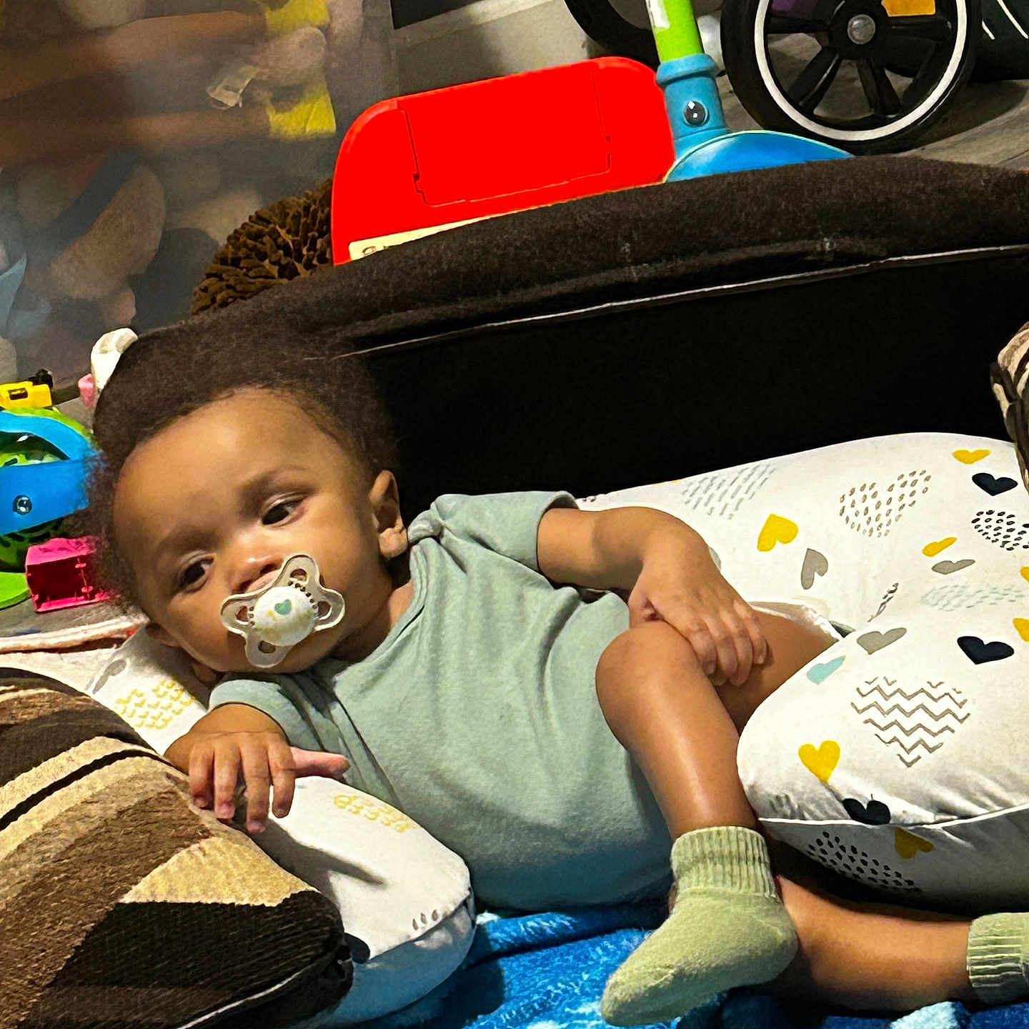 Donta is registered to the contest to win money with this photo: baby, blanket, child, clothing, colorful, comfort, cushion, floor, furniture, home, indoor, pacifier, person, playroom, relaxed, resting, sock, toddler, toy, tricycle
