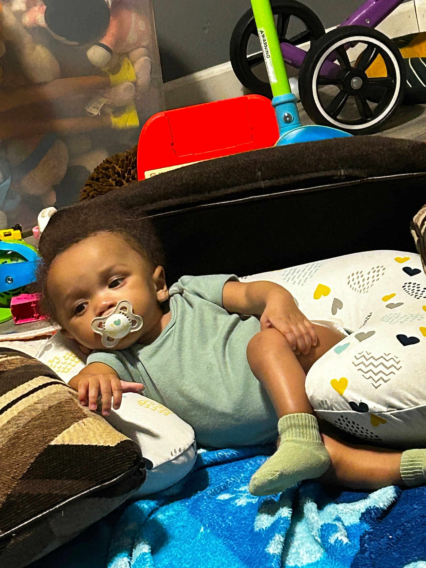 Donta is registered to the contest to win money with this photo: toddler, pacifier, blanket, cushion, child, toy, tricycle, sock, indoor, relaxed, baby, clothing, floor, playroom, comfort, home, colorful, furniture, person, resting
