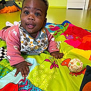 Ilétou participe au concours pour gagner de l'argent avec cette photo : baby, child, dribble, playmat, colorful, indoor, toy, happy, crawling, clothing, patterned, face, hand, floor, expression, person, curly_hair, smiling, infant, bright