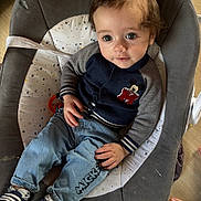 Aïden participe au concours pour gagner de l'argent avec cette photo : toddler, child, baby_seat, denim_jeans, sweater, mickey_mouse, indoor, floor, footwear, baby_shoes, curly_hair, casual_clothing, relaxed, home, wood_floor, foot, comfort, cute, portrait, seated