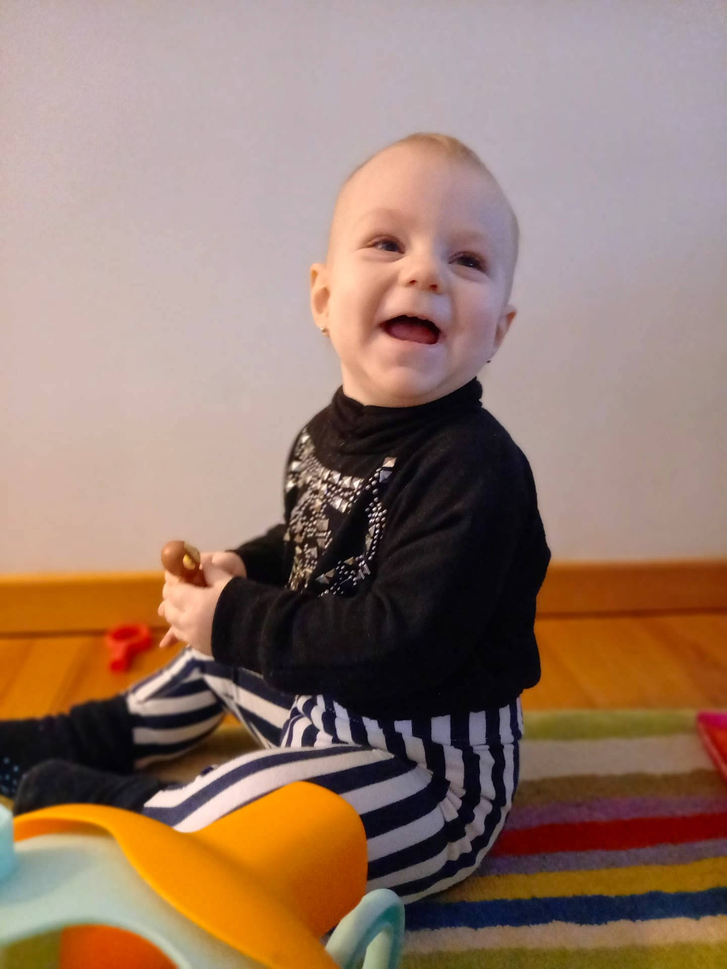 Elodie participe au concours pour gagner de l'argent avec cette photo : baby, baby_playing_with_toys, baby_toddler_clothing, child, comfort, facial_expression, finger, flooring, fun, happy, orange, person, product, riding_toy, sitting, skin, sleeve, smile, t_shirt, toddler