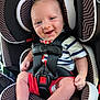 baby, car_seat, graco, smiling, happy, child, infant, seatbelt, clothing, red_shorts, striped_shirt, face, head, legs, feet, hand, safety, child_seat, portrait, indoor