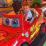 Eliano participe au concours pour gagner de l'argent avec cette photo : toddler, child, pacifier, toy_car, red_car, carnival, amusement_ride, indoor, colorful, playground, seatbelt, toy, vehicle, entertainment, young_child, fun, bright_colors, smiling, face, person