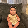 baby, child, smiling, sitting, couch, gray_couch, hair_bows, indoors, window_air_conditioner, curtains, cute, portrait, infant, happy, skin, clothing, furniture, home, person, relaxed