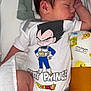 baby, newborn, sleeping, onesie, clothing, dragon_ball, character_print, blanket, mittens, pillow, cute, infant, peaceful, soft, indoors, laying_down, person, child, resting, sleep