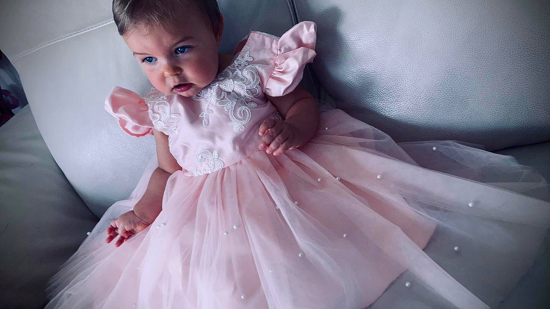 Arya participe au concours pour gagner de l'argent avec cette photo : baby, baby_toddler_clothing, bridal_clothing, bridal_party_dress, day_dress, dress, embellishment, face, flash_photography, gown, hair, hairstyle, happy, head, iris, person, pink, skin, sleeve, toddler