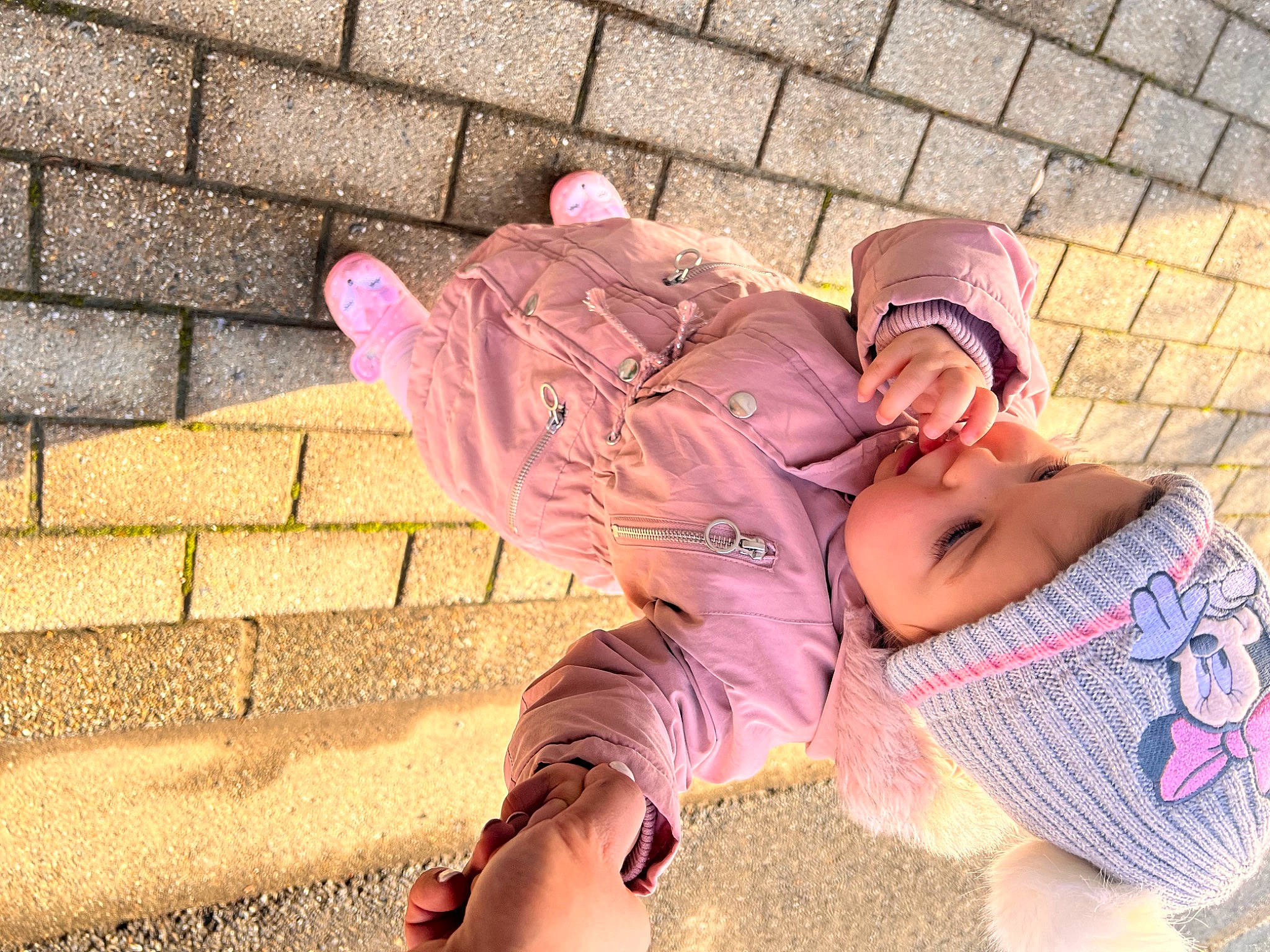 Arya participe au concours pour gagner de l'argent avec cette photo : baby_toddler_clothing, brick, brickwork, child, comfort, flooring, foot, grass, happy, headwear, human_leg, leg, leisure, person, pink, purple, shoe, sitting, smile, textile