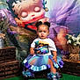 toddler, child, girl, tutu, colorful_clothing, shoes, braided_hair, cartoon_backdrop, flowers, wooden_crates, green_carpet, sitting, portrait, indoor, decor, cute, expression, earrings, birthday_shirt, basket