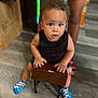 Xykie joined the competition — help win amazing prizes! toddler, child, curly_hair, black_shirt, colorful_socks, indoor, wooden_floor, wooden_stool, person, legs, hands, face, eyes, expression, sitting, floor, adult, background, clothing, footwear
