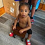 Daxaiireo joined the competition — help win amazing prizes! toddler, child, indoor, floor, slippers, elmo, wooden_cart, box, shorts, person, curious, bare_chest, footwear, carpet, wall, standing, toy, expression, young, home