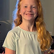 Riley is registered to the contest to win money with this photo: child, smiling, red_hair, long_hair, indoor, light_colored_shirt, portrait, young, happy, person, casual_clothing, face, standing, home, cozy, natural_light, cute, childhood, human, friendly