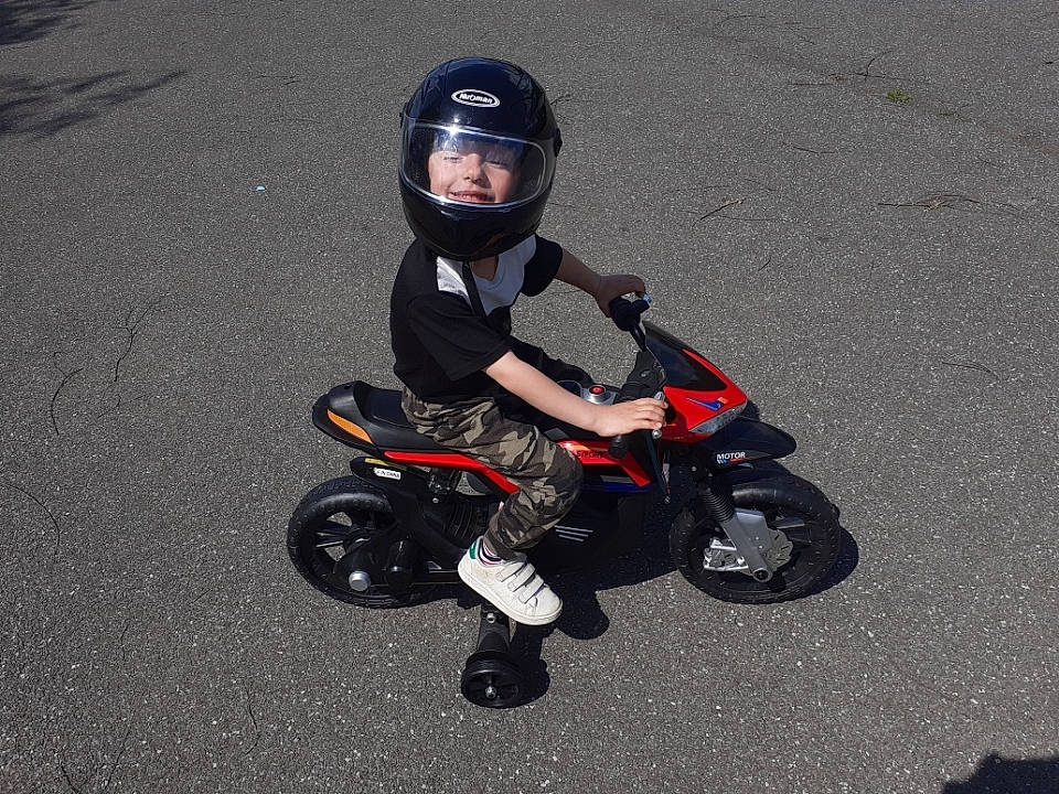 Lucas participe au concours pour gagner de l'argent avec cette photo : asphalt, automotive_design, automotive_exterior, automotive_lighting, automotive_tire, automotive_wheel_system, fender, headwear, helmet, land_vehicle, motor_vehicle, person, personal_protective_equipment, rim, rolling, sports_gear, synthetic_rubber, tire, toddler, tread