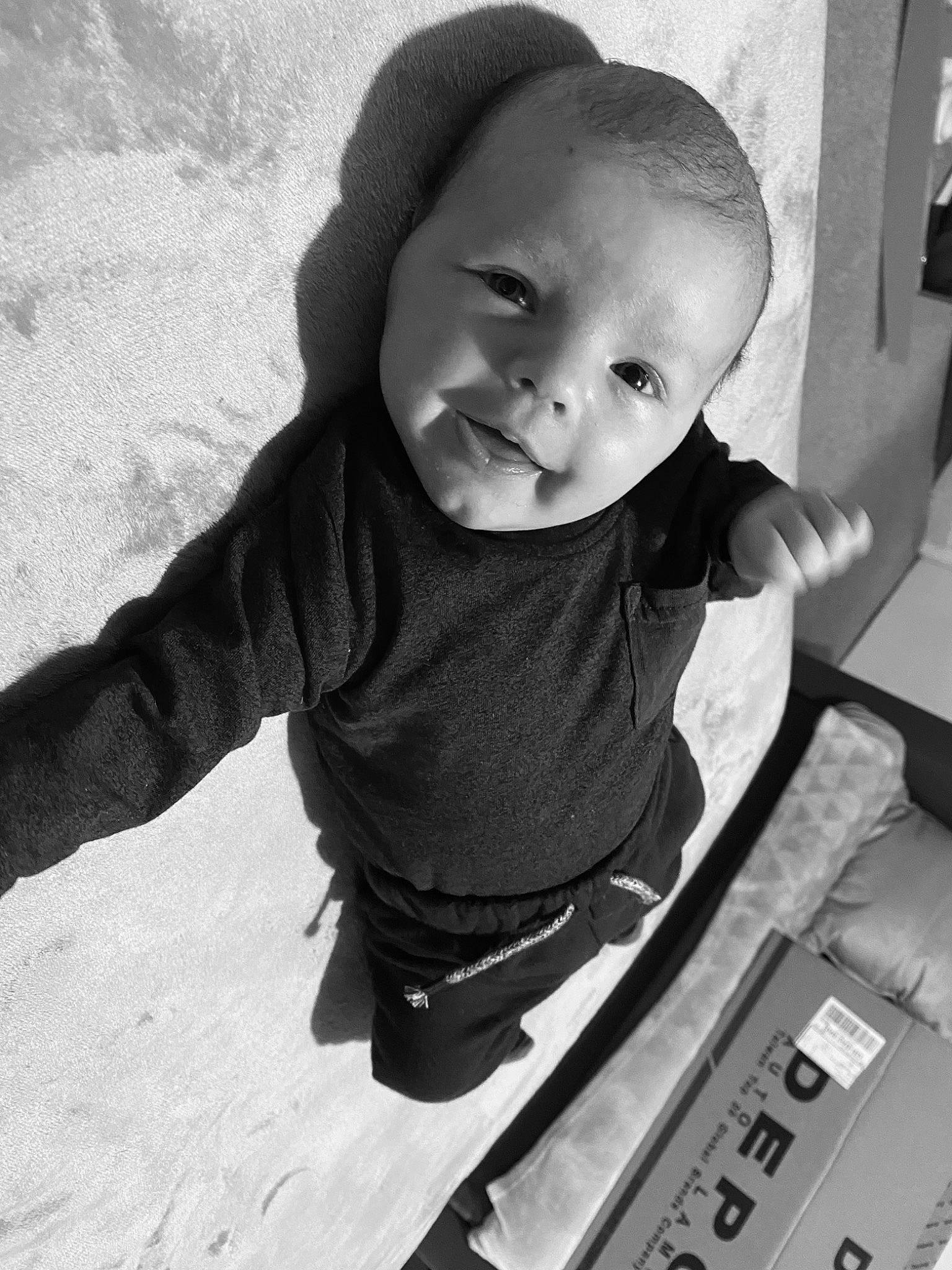 Jaxson is registered to the contest to win money with this photo: baby, black_and_white, cap, child, eyebrow, flooring, fun, hair, hand, happy, human_body, monochrome, monochrome_photography, nose, person, sitting, sleeve, smile, style, t_shirt