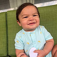 Xavier joined the competition — help win amazing prizes! baby, child, smiling, onesie, banana_pattern, green_couch, brush, hand, indoor, cute, happy, infant, person, holding, seated, short_hair, skin, face, arm, furniture