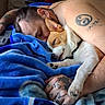 dog, puppy, sleeping, human, person, cuddle, snuggling, blanket, blue_blanket, indoors, bed, cozy, resting, closed_eyes, pet, companion, tattoo, yin_yang, portrait, relaxed