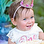 Ainhoa joined the competition — help win amazing prizes! child, baby, toddler, crown, headband, cake, frosting, birthday, portrait, blue_eyes, smile, lace_dress, earring, outdoor, greenery, celebration, bokeh, cute, first_birthday, birthday_smash