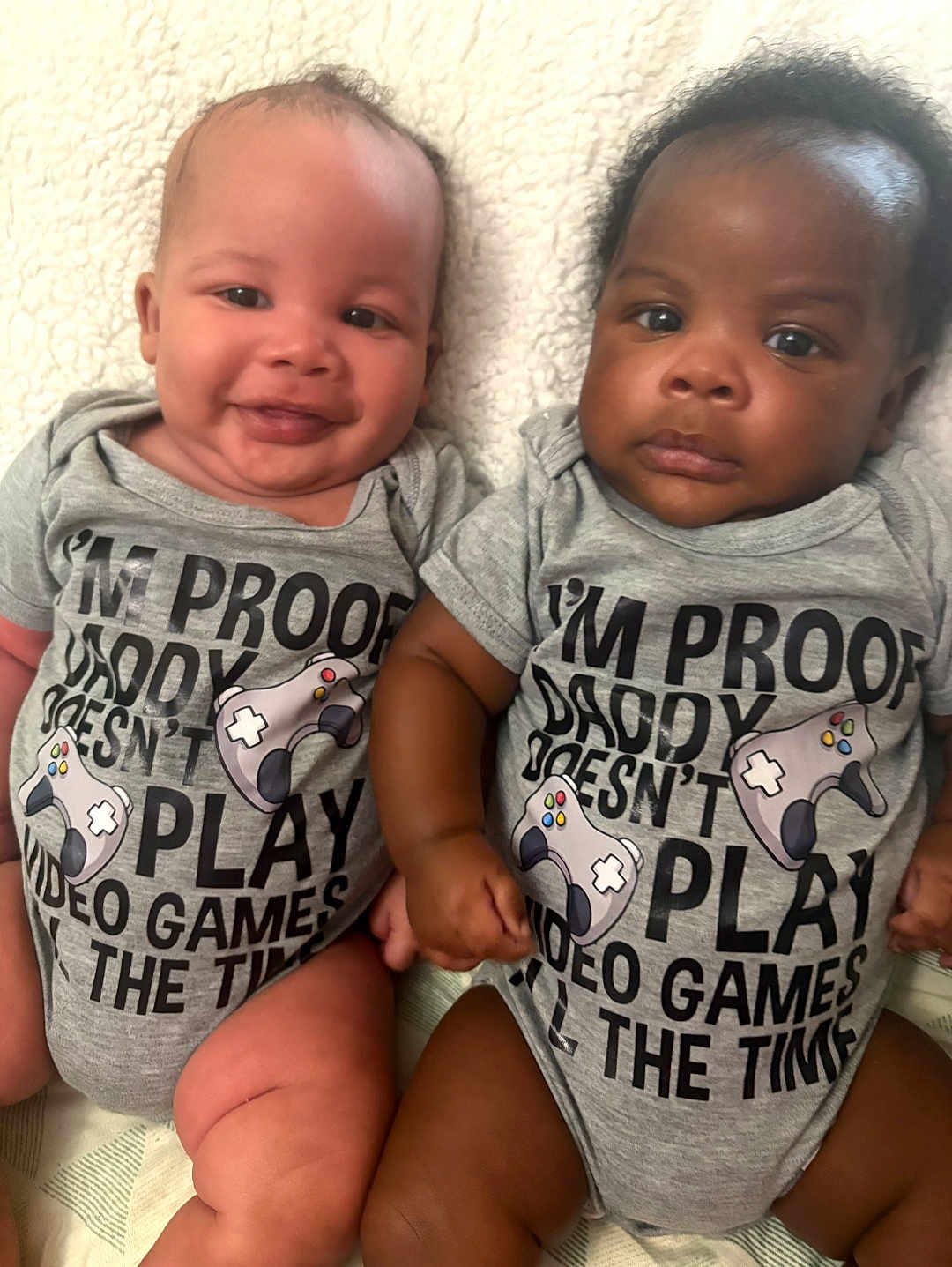 Keith And Keion joined the competition — help win amazing prizes! baby, infant, toddler, smiling, serious, onesie, clothing, gray, text, video_games, controller, cute, sitting, blanket, indoors, two_babies, diversity, portrait, holding_hands, closeup