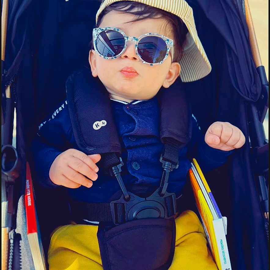 Ilan Bounia participe au concours pour gagner de l'argent avec cette photo : baby, baby_accessory, blue_jacket, book, cap, casual, child, cool, cute, fashion, hat, infant, outdoor, person, portrait, seatbelt, stroller, sunglasses, sunny, yellow_pants
