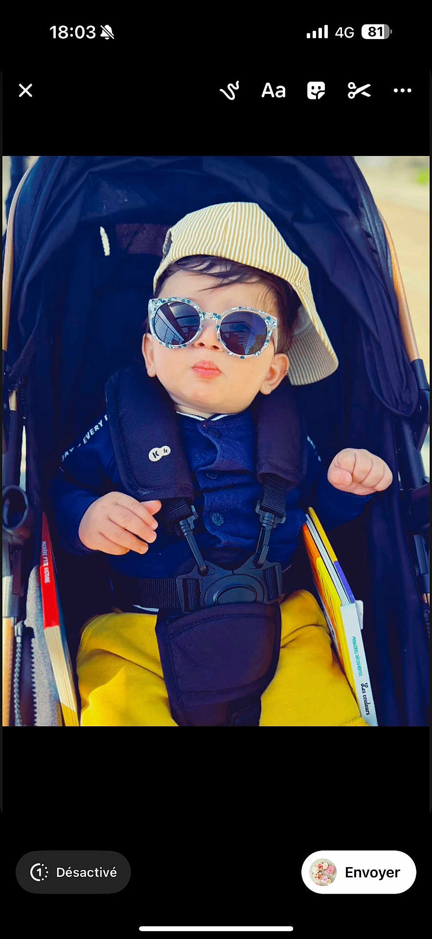 Ilan Bounia participe au concours pour gagner de l'argent avec cette photo : baby, child, stroller, sunglasses, hat, cap, yellow_pants, blue_jacket, book, outdoor, sunny, cute, fashion, portrait, infant, person, seatbelt, cool, baby_accessory, casual