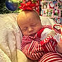 baby, sleeping, pajamas, red_and_white, striped_clothing, bow, christmas_tree, christmas_ornament, gift_wrapping, holiday, present, blanket, cozy, indoors, cute, festive, child, face, peaceful, candy_cane