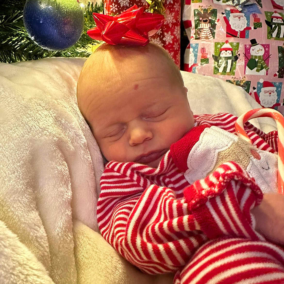 Asher is registered to the contest to win money with this photo: baby, blanket, bow, candy_cane, child, christmas_ornament, christmas_tree, cozy, cute, face, festive, gift_wrapping, holiday, indoors, pajamas, peaceful, present, red_and_white, sleeping, striped_clothing
