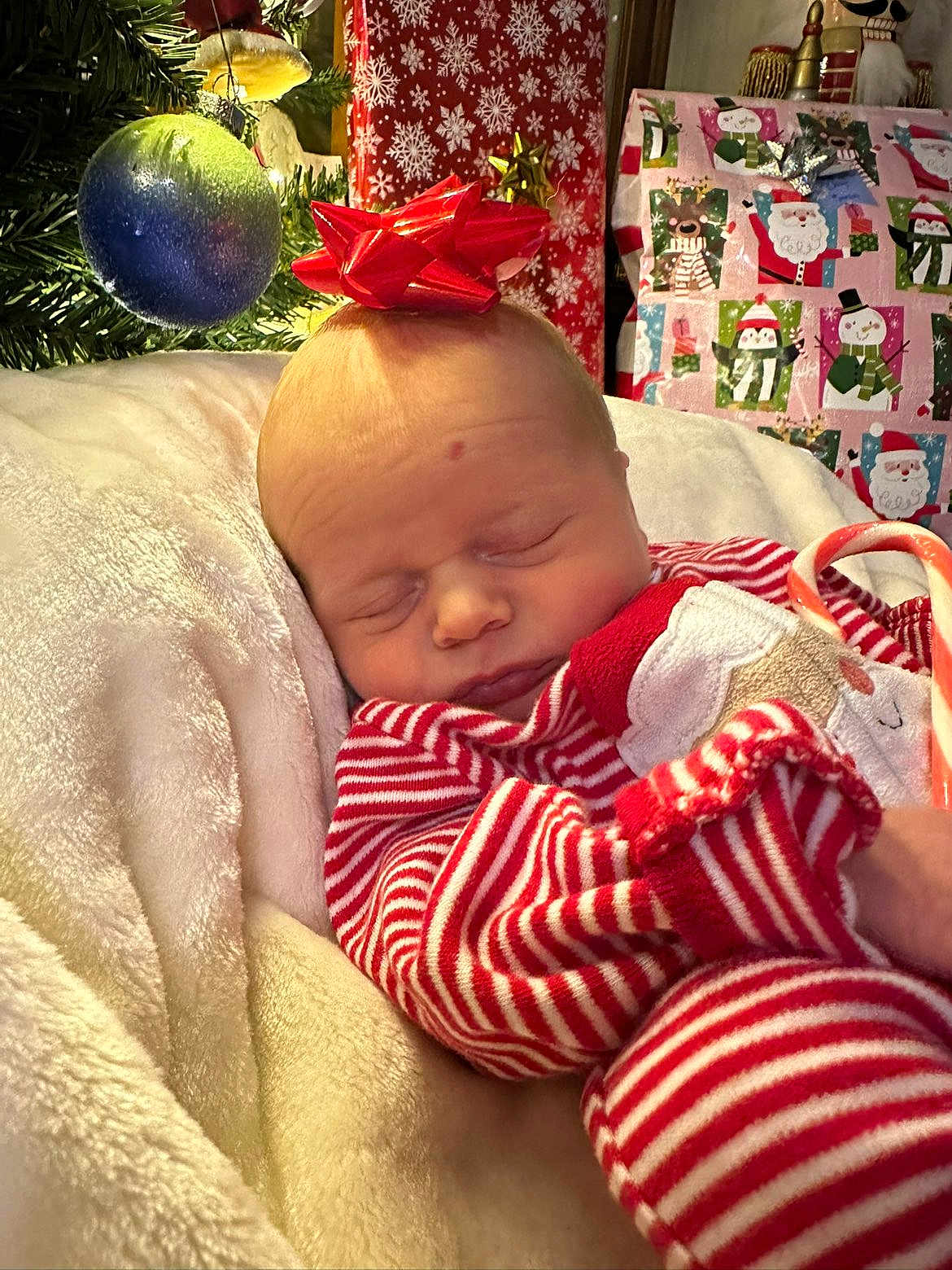 Asher is registered to the contest to win money with this photo: baby, sleeping, pajamas, red_and_white, striped_clothing, bow, christmas_tree, christmas_ornament, gift_wrapping, holiday, present, blanket, cozy, indoors, cute, festive, child, face, peaceful, candy_cane