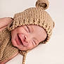 Enzo is registered to the contest to win money with this photo: baby, smiling, knitted_hat, knitted_clothing, infant, sleeping, cute, close_up, face, newborn, soft_texture, beige, cozy, happy, portrait, child, apparel, headwear, peaceful, lying_down