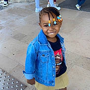 Myriam participe au concours pour gagner de l'argent avec cette photo : child, smiling, braided_hair, beads, denim_jacket, tshirt, skirt, sneakers, floor, tiles, outdoor, person, footwear, standing, people, background, urban, fashion, casual_clothing, happy